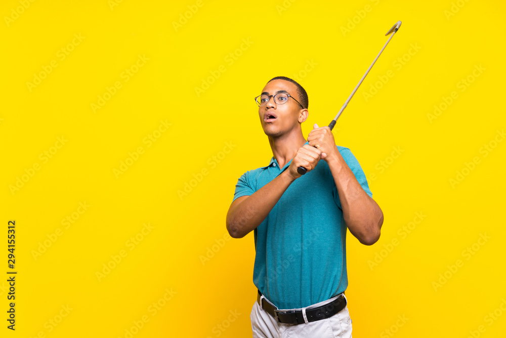 Afro American golfer player man over isolated yellow background Afro American golfer player man over isolated yellow background
