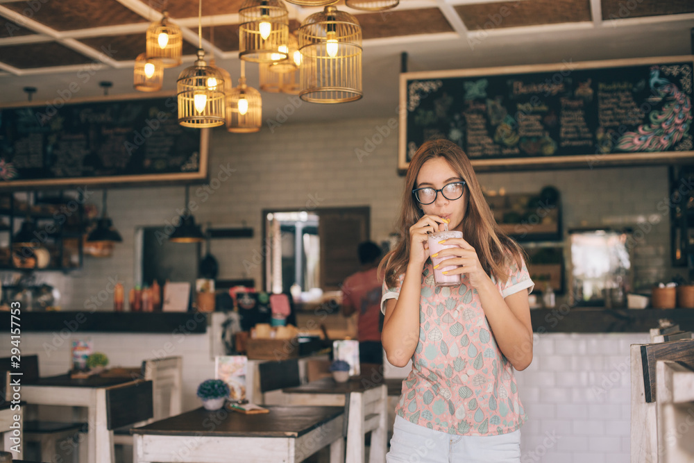 Teen girl drinking smoothie in cafe