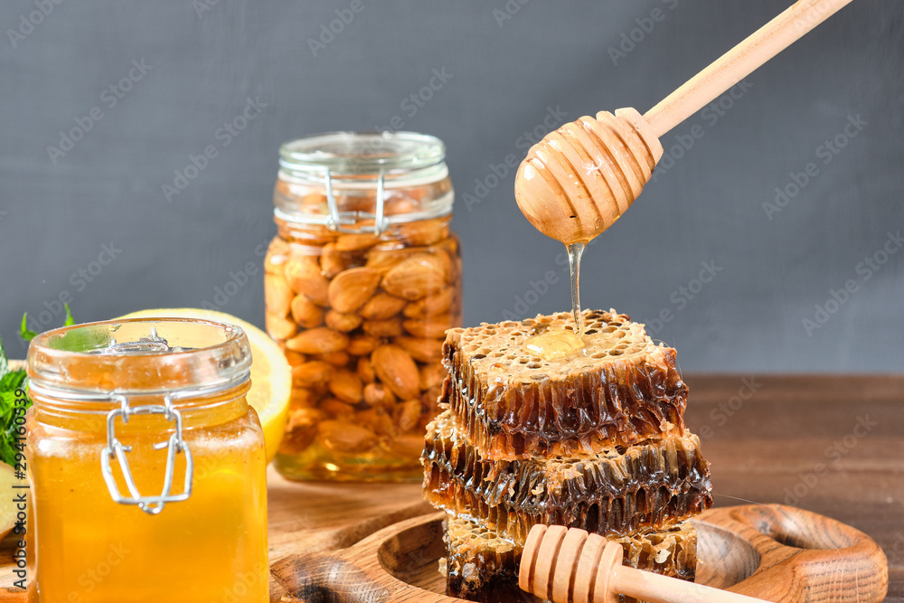 honey in honeycombs on a wooden plate and golden honey in a jar with nuts and comb for honey with lemon and ginger on a brown wooden background honey in honeycombs on a wooden plate and golden honey in a jar with nuts and comb for honey with lemon and ginger on a brown wooden background