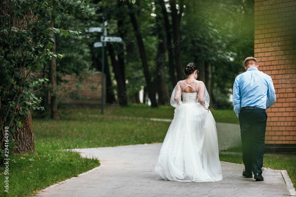 Bride and groom at wedding Day walking Outdoors on spring nature. Bridal couple, Happy Newlywed woman and man embracing in green park. Loving wedding couple outdoor. Bride and groom