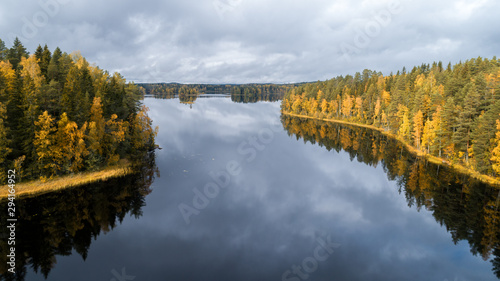Autumn yellow forest and clouds reflected in the water. Autumn trees in forest. Clean lake in the summer forest. Camping by the lake. Nature reserve in Finland.