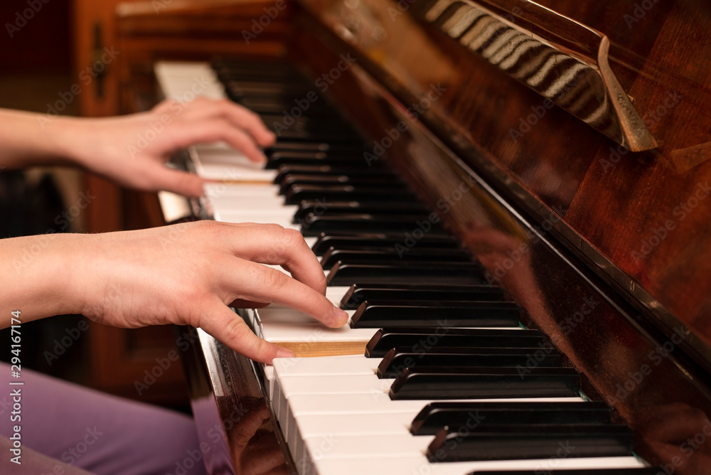 A young teenage girl playing at home on the piano, her hands gracefully playing a familiar tune. Music education helps the girl to develop