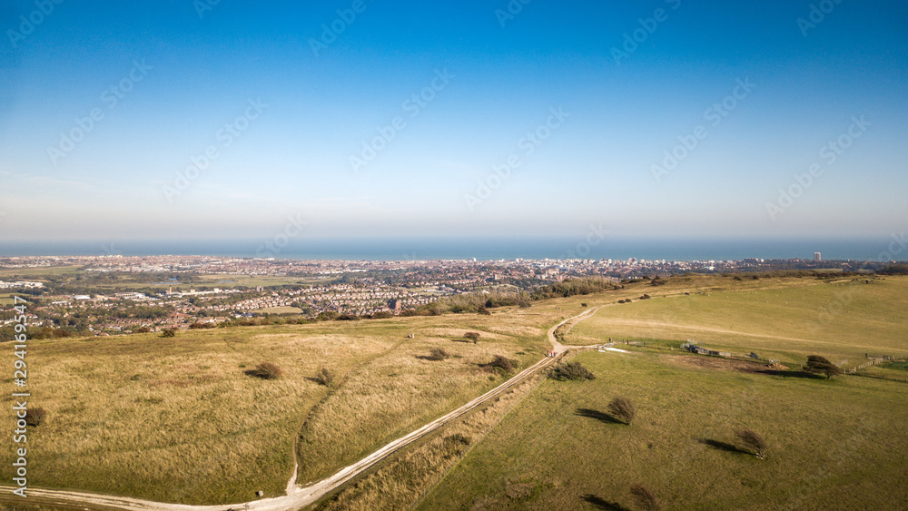 Obraz premium Eastbourne and The South Downs, East Sussex, England. An aerial view of the South Downs Way leading towards the popular south coast seaside resort.