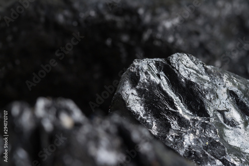 Black coal mine close-up with soft focus. Anthracite coal bar on dark background. Natural black coal bars for background. Industrial coal nuggets close up photo