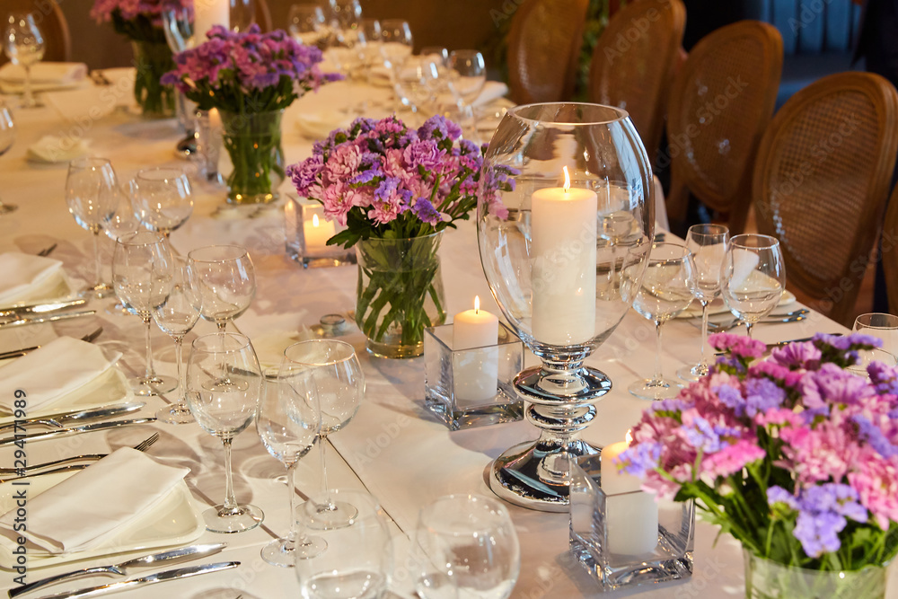 Table setting for guests in a restaurant, on the table forks and glasses for wine - flowers in a vase and a candle on the table Table setting for guests in a restaurant, on the table forks and glasses for wine - flowers in a vase and a candle on the table