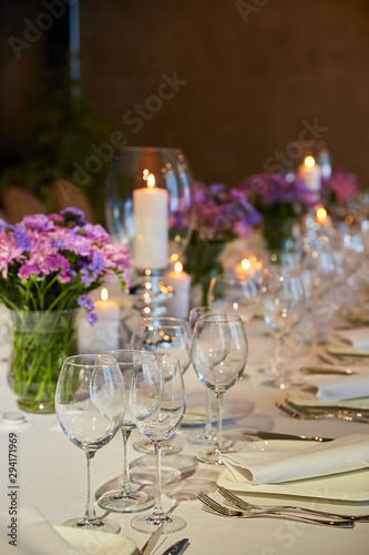 Table setting for guests in a restaurant, on the table forks and glasses for wine - flowers in a vase and a candle on the table