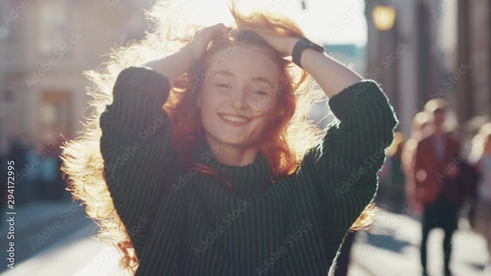 Gorgeous happy ginger young woman walking in the street smiling having positive mood enjoying sunlight spring weather. Unique female beauty.