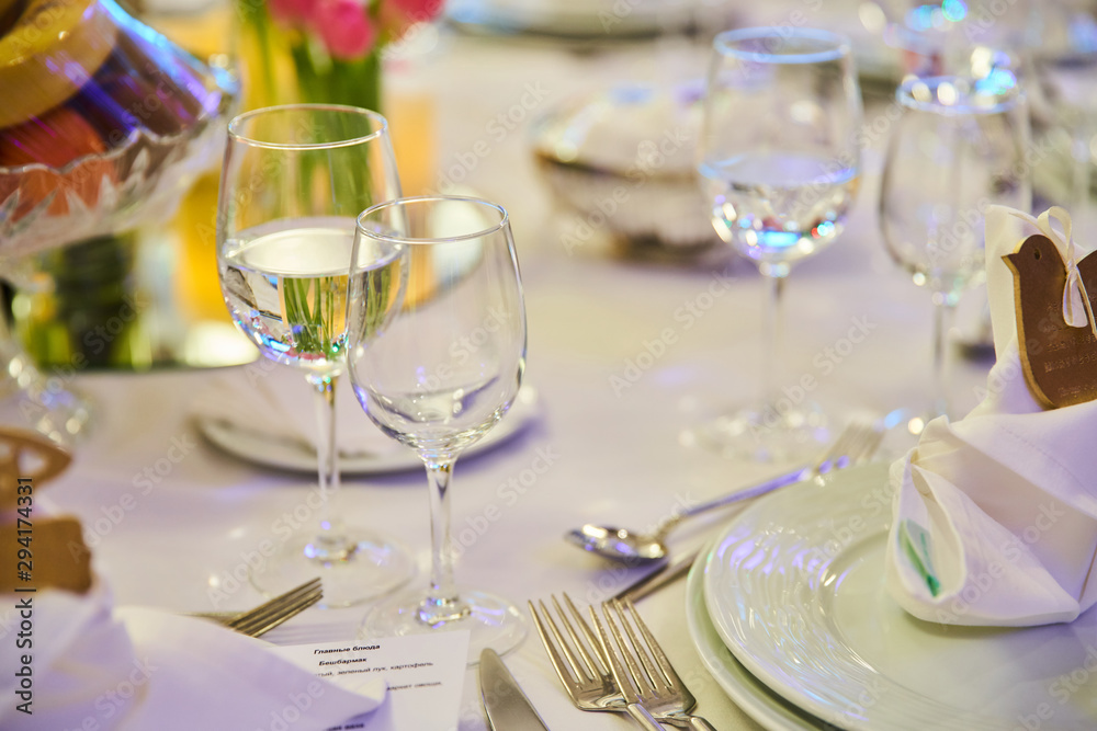 Table setting for guests in a restaurant, on the table forks and glasses for wine - flowers in a vase and a candle on the table Table setting for guests in a restaurant, on the table forks and glasses for wine - flowers in a vase and a candle on the table