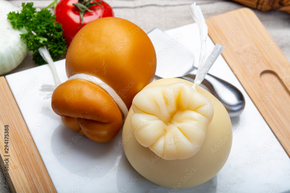Italian provolone or provola caciocavallo hard and smoked cheeses in teardrop form served on white marble plate close up