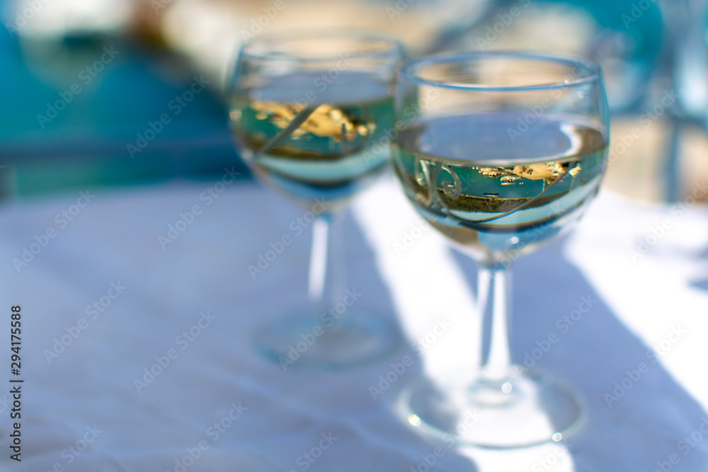 White wine served outside on balcony on glass table with sea view White wine served outside on balcony on glass table with sea view