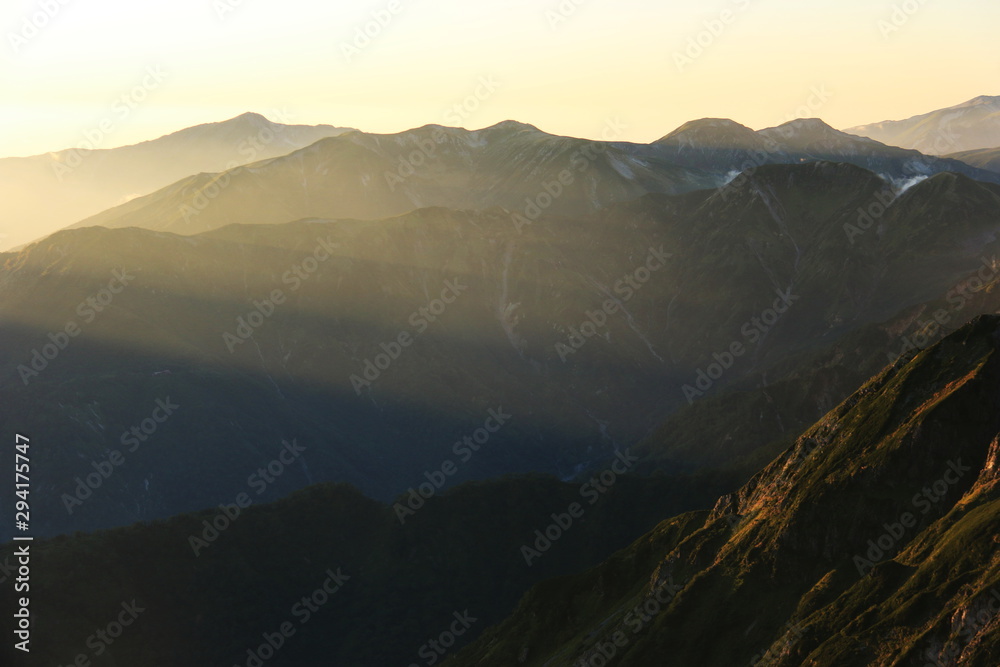 北アルプス　槍穂高大キレット縦走　南岳山頂からの風景　夕陽の光芒と笠ヶ岳のシルエット