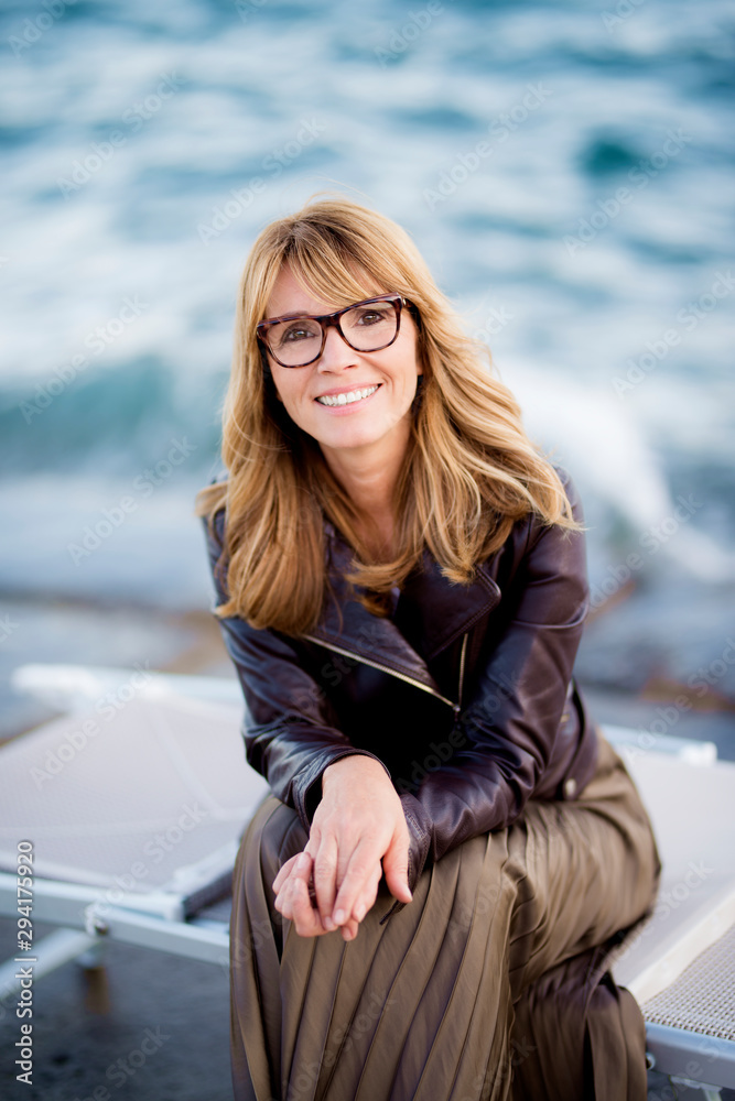 Portrait of beautiful woman sitting at the ocean and relaxing Portrait of beautiful woman sitting at the ocean and relaxing