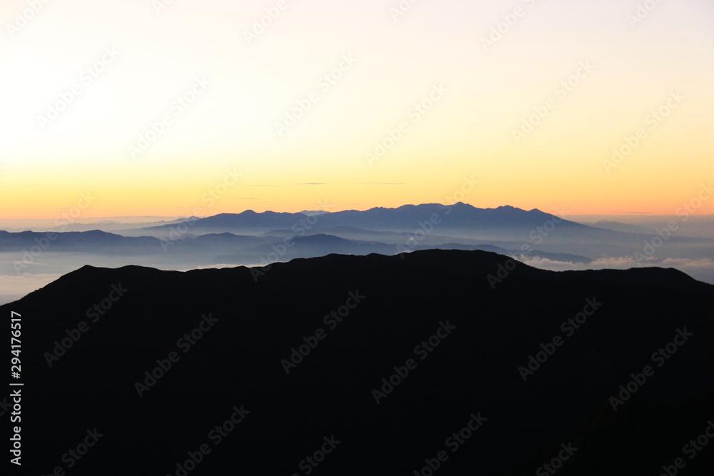 北アルプス　槍穂高連峰縦走　南岳山頂からの風景　蝶ヶ岳越しの朝焼けに映える八ヶ岳遠景