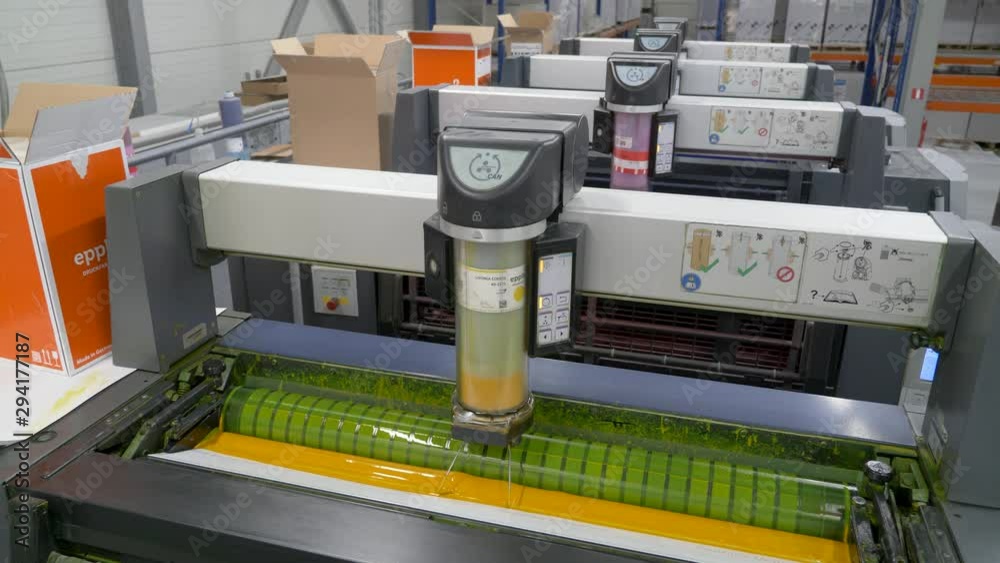 A static footage of the slow movement of colored cartridges of printing machines at printing house showing the process of ink being transferred from inked surface to print media/paper.Front view.
