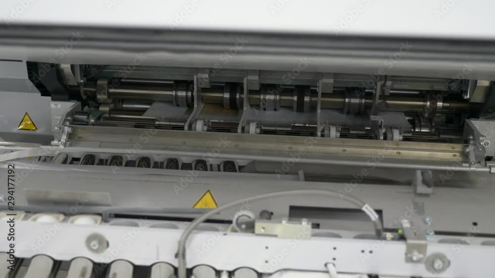 A close up static view of printed sheets of paper moving rapidly in a printing machine at printing press. A close up static view of printed sheets of paper moving rapidly in a printing machine at printing press.