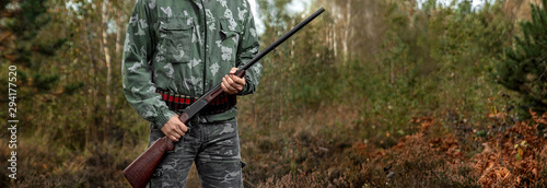 Photographie Hunter man in camouflage with a gun during the hunt in search of wild birds or game on the background of the autumn forest