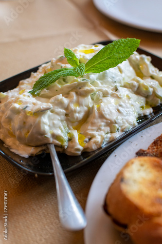 Tzatziki dip or sauce from Southeast Europe and Middle East made of salted strained yogurt mixed with cucumbers, garlic, salt, olive oil, vinegar or lemon juice, and dill, mint, parsley and thyme. photo