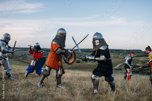 Knights in armour and helmets fight with swords