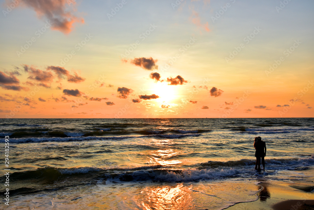 man stood by the sea with his women in his arms and watched the sun rise in the morning. He looked happy and warm   