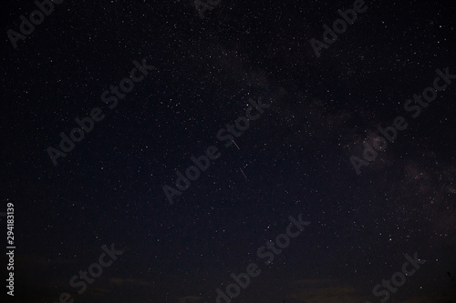 Amazing starry night sky above lake in mountains. Beautiful night sky with Milky Way and falling stars. Breathtaking landscape. View on sky from camp tent