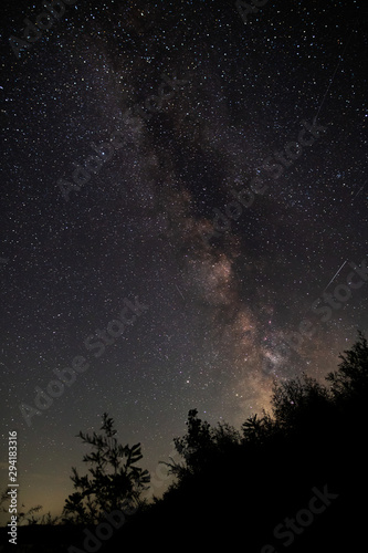 Amazing Milky Way , starry night sky with falling stars above lake and trees in mountains. Beautiful night sky. Breathtaking landscape. View on sky from camp tent in woods