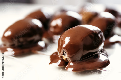 Dates in chocolate, dessert. Confectioner pours chocolate over dessert. Macro, close-up.