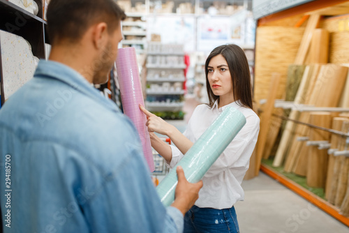 Couple choosing wallpapers color in hardware store