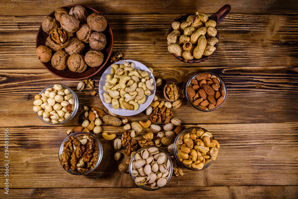 Various nuts (almond, cashew, hazelnut, pistachio, walnut) in bowls on a wooden table. Vegetarian meal. Healthy eating concept. Top view Various nuts (almond, cashew, hazelnut, pistachio, walnut) in bowls on a wooden table. Vegetarian meal. Healthy eating concept. Top view