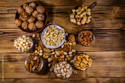 Various nuts (almond, cashew, hazelnut, pistachio, walnut) in bowls on a wooden table. Vegetarian meal. Healthy eating concept. Top view