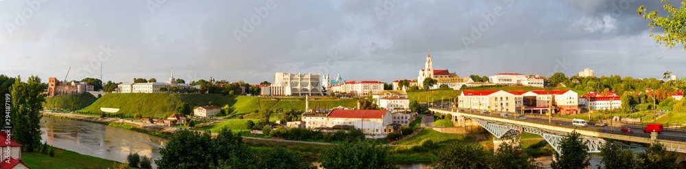 Panoramic view of the city of Grodno, the embankment, the Neman river and the old city. Autumn evening, the city in the sunshine on a background of dark clouds.