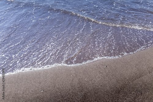 Sea surf on the beach with black volkanic sand. photo