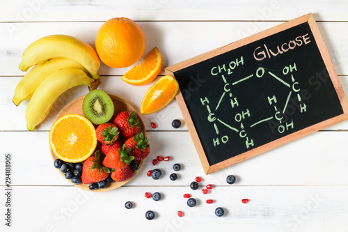 Glucose molecule on blackboard with mixed fresh fruits salad photo