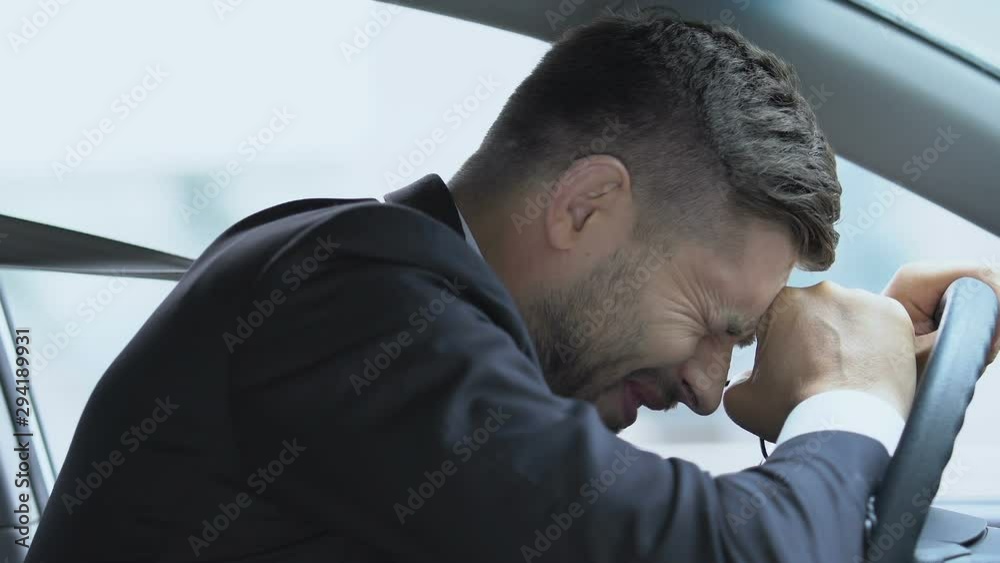 Distressed man suffering bad headache in car, result of stressful job overwork Distressed man suffering bad headache in car, result of stressful job overwork