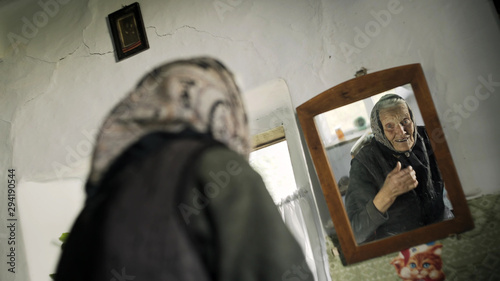 Elderly lady adjusting her kerchief in a mirror
