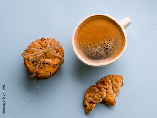 A cup of coffee and american cranberry cookies on blue background. Top view. Bewerages, coffee lovers and morning menu concept. photo