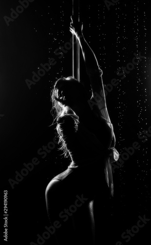 Beautiful wet athletic busty elegant blonde girl performs artistic elements of an exotic dance on the rain. Health, lifestyle, sports, black white monochrome design. Copy space.