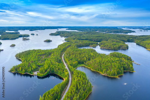 Aerial view of road between green summer forest and blue lake in Finland photo