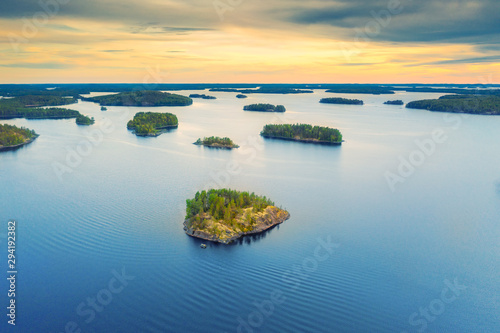 Aerial view of of small islands on a blue lake Saimaa. Landscape with drone. Blue lakes, islands and green forests from above on a cloudy summer morning. Lake landscape in Finland.