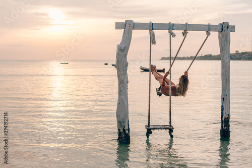 Girl relaxing in swings on sunset beach photo