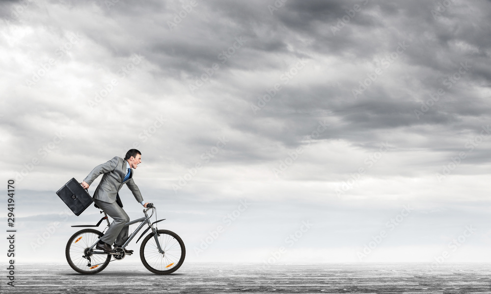 Obraz premium Man wearing business suit riding bicycle outdoor.