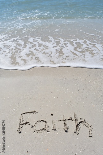 Vertical background of faith written in sand on the beach