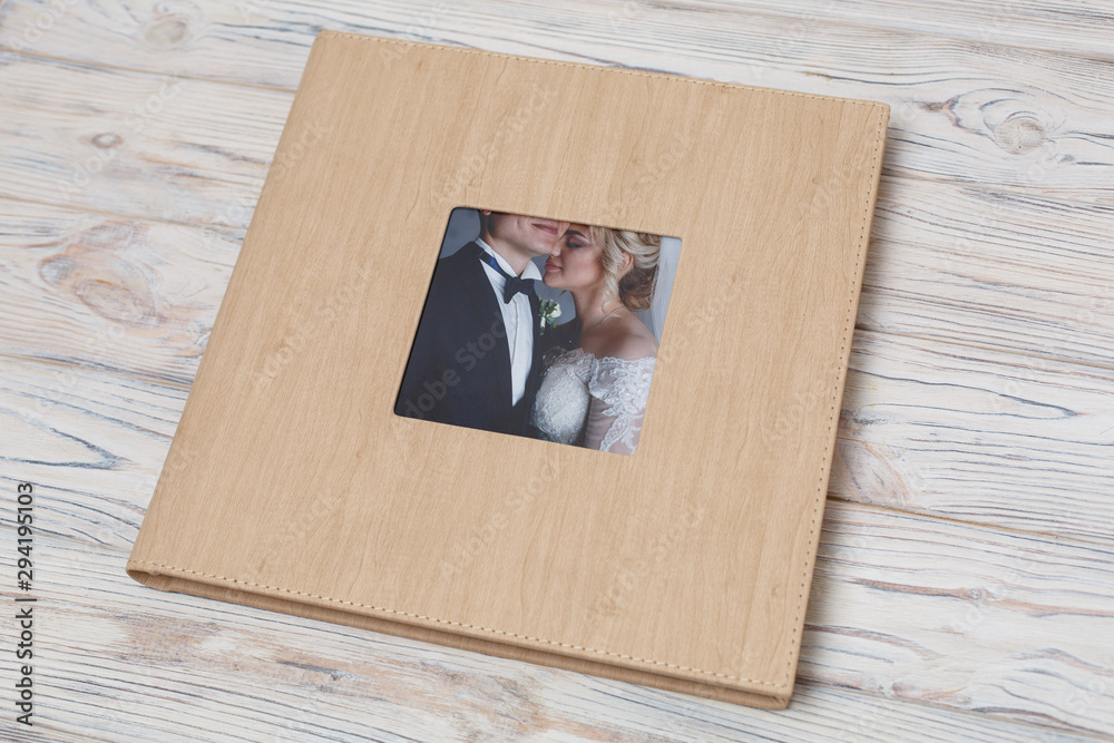 family photo book with leather cover. Wedding photo album with insert with  copy space for text. Beige photobook on a wooden background.Photoalbum with  a hard cover on a wooden background. foto de
