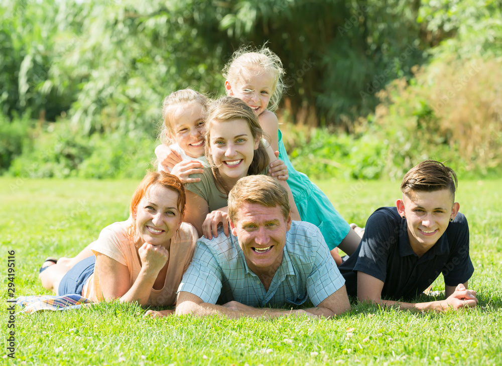 Fototapeta premium Portrait of big happy family with parents and four children on green lawn outdoors