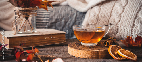 Panel kuchenny z motywem Cozy autumn or winter at home. A cup of tea, autumn casts a book a garland on a wooden table near a bed with warm plaids. Lifestyle autumn hygge lagom?concept of a holiday and autumn weekend.Banner