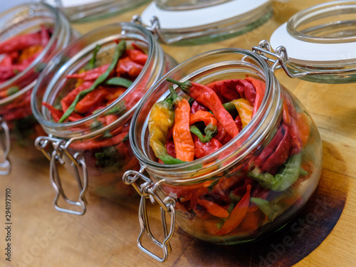 Angled view of open glass jars with canned hot pepper. The jar is prepared for clogging after pickling. The culinary delicacy of long storage.