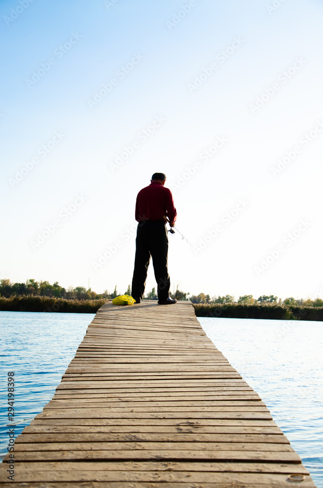 fisherman on a bridge near a blue lake