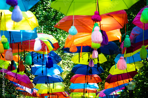 colored rainbow umbrellas on a background of green trees