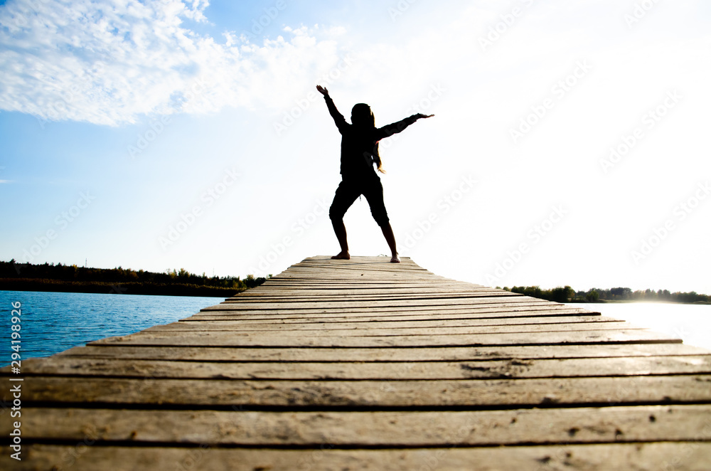 girl doing yoga and sports martial arts on a bridge on a lake girl doing yoga and sports martial arts on a bridge on a lake