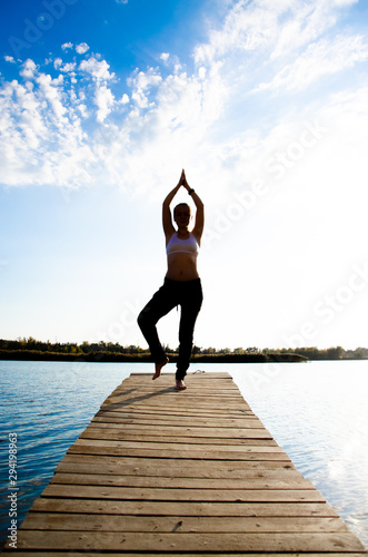 girl doing yoga and sports martial arts on a bridge on a lake