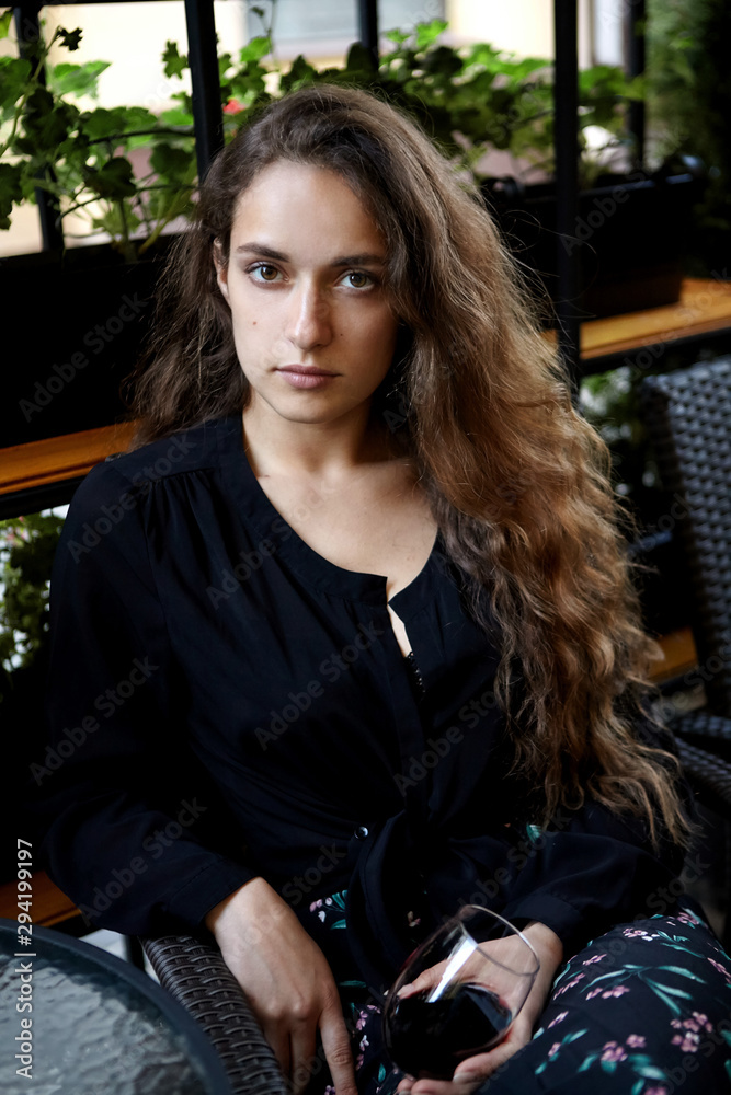 Fototapeta premium Closeup portrait of long haired curly beautiful girl. With glass of wine.